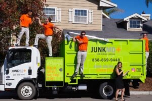 Team providing professional junk removal services Kent WA with bright green truck and friendly staff in front of a residential property.